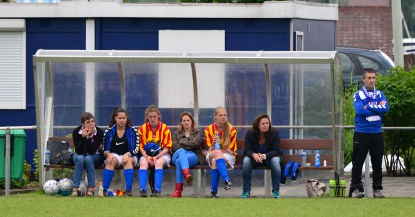 Jonge wisselspelers en speelsters met blessures.  De trainer kijkt toe.
